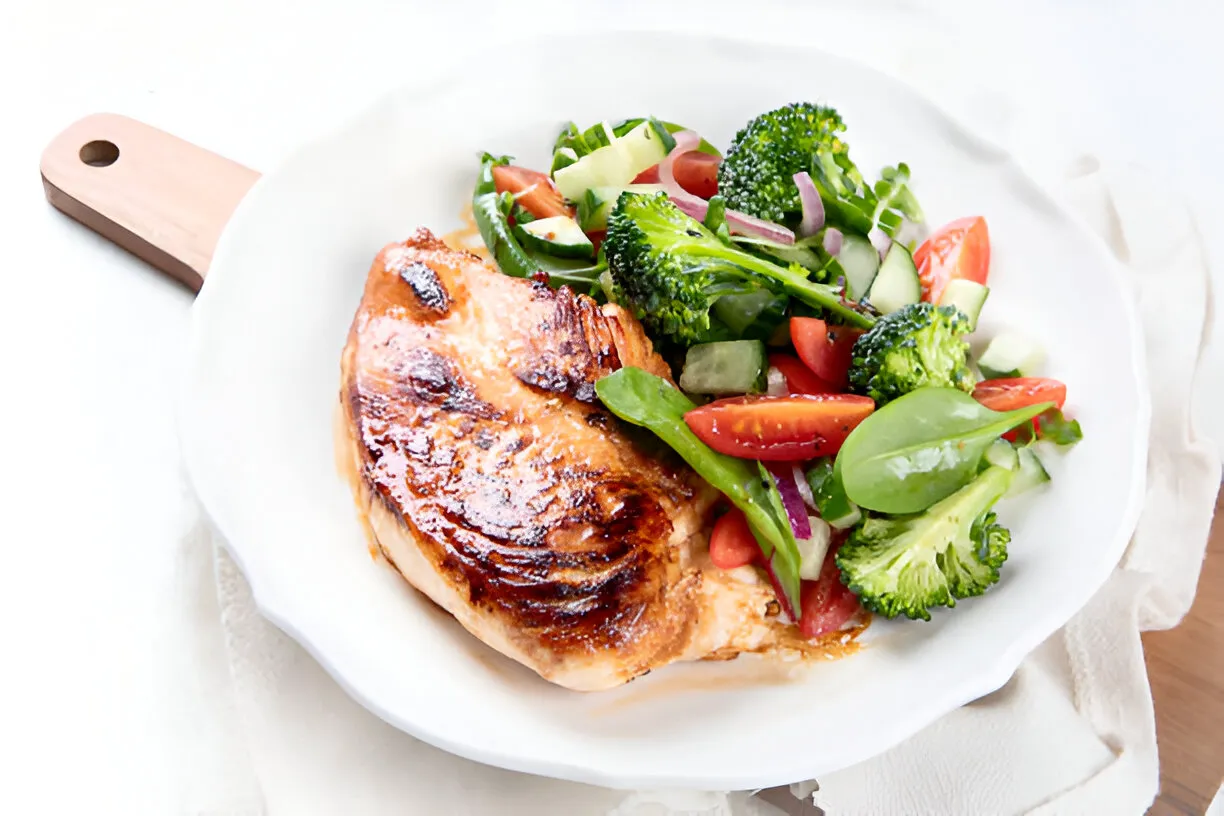 Un plat de poulet rôti entouré de légumes d'hiver (betteraves, poireaux) sur une table en bois rustique